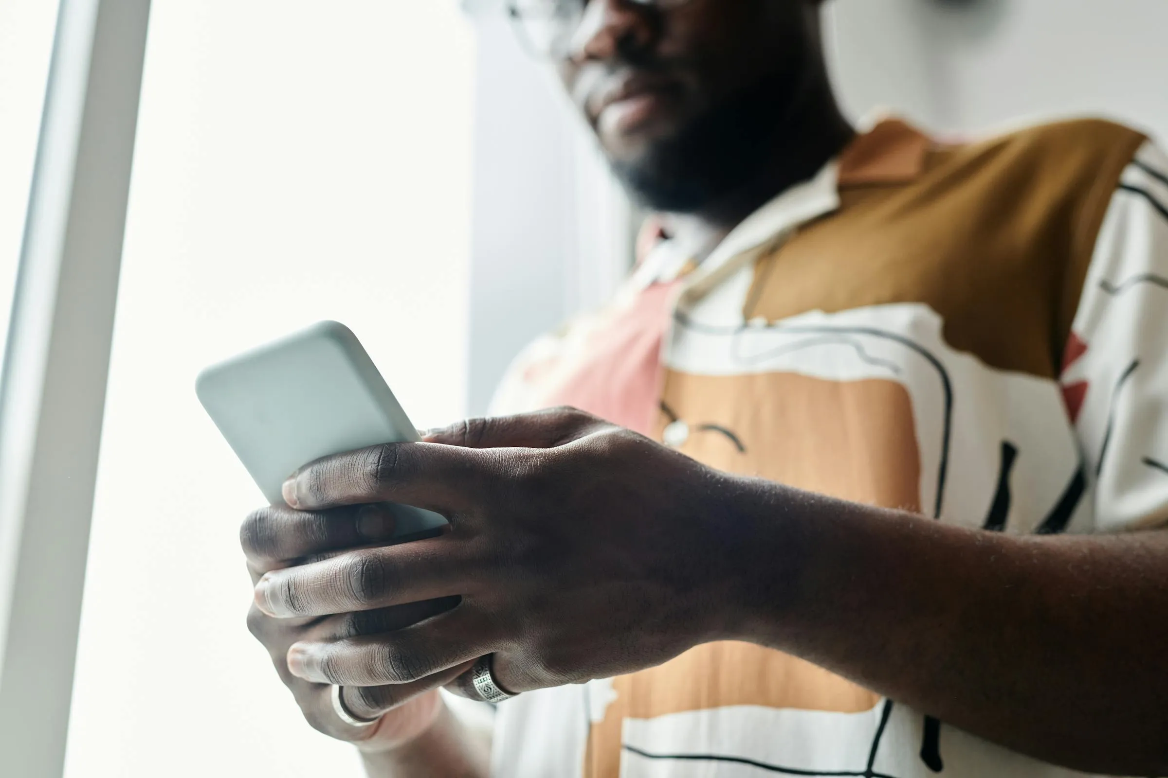 Close-up of a person using their smartphone by a window