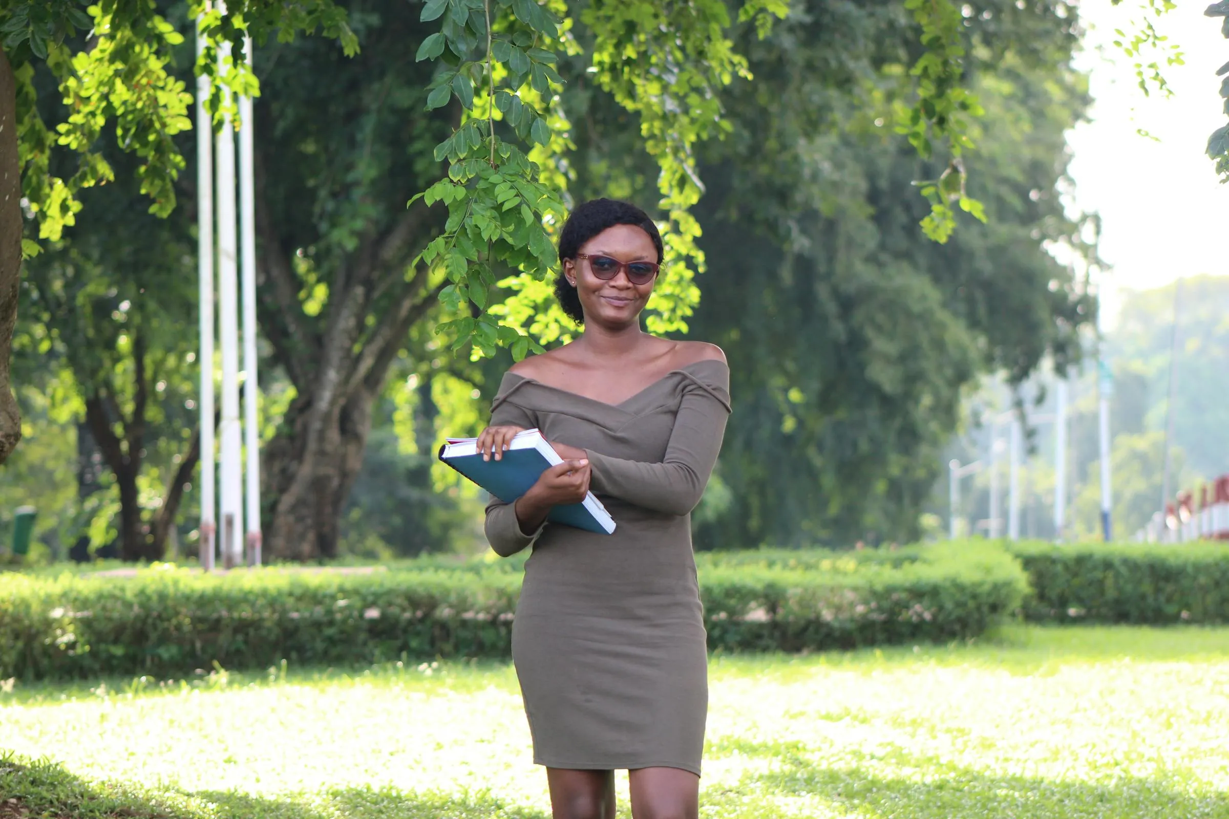 Confident young woman with books walking across a university campus on a sunny day